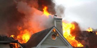 House engulfed in flames with heavy smoke from the roof