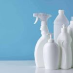 White plastic cleaning bottles against a blue background