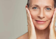 Close-up portrait of a smiling woman gently holding her face