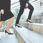 Two businesspeople in formal wear walking up stairs