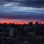 city skyline at dusk with dramatic clouds and orange horizon