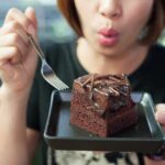 woman holding a plate with a slice of chocolate cake