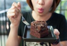 Refined Sugar and Its Effects on Mortality and the Brain woman holding a plate with a slice of chocolate cake