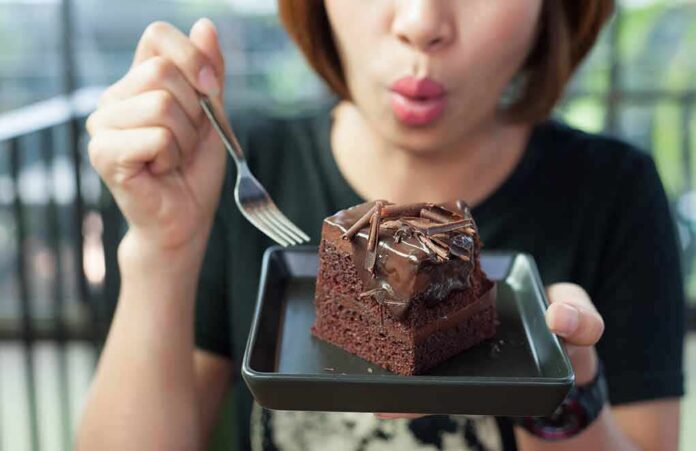shutterstock_1022214640 woman holding a plate with a slice of chocolate cake