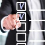 person in suit pointing at a digital checklist