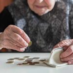 Elderly person counting coins on a table