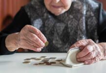 Elderly person counting coins on a table