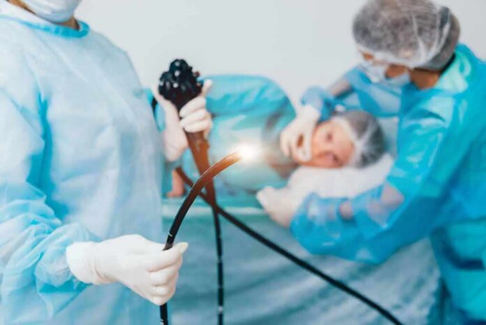 Medical staff preparing endoscope near patient on hospital bed