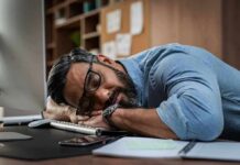 man sleeping at desk with head on arms