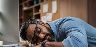 man sleeping at desk with head on arms