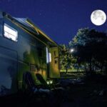 RV under a full moon at a forest campsite