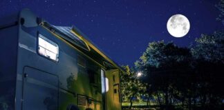 RV under a full moon at a forest campsite