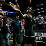 Basketball player in arena high-fives fans while wearing headphones