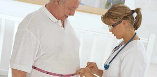 A healthcare professional measuring a patients waist with a tape measure