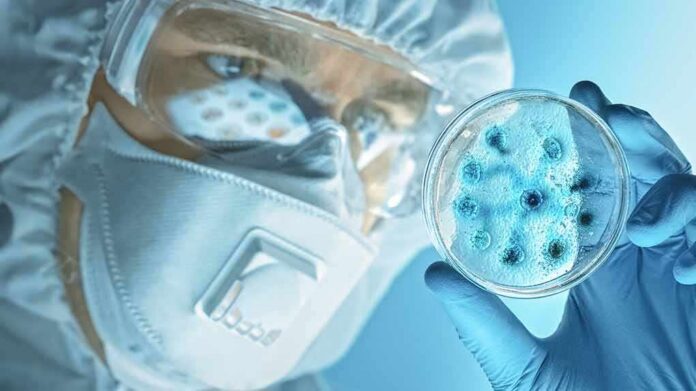 shutterstock_1672672939 Scientist in protective gear examining a petri dish