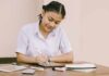 Student writing at a desk with school supplies