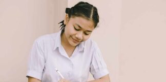 Student writing at a desk with school supplies
