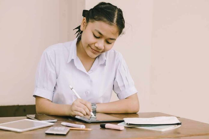 Student writing at a desk with school supplies