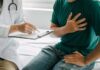 Uncovering New Drivers of Heart Disease Patient holding chest while doctor takes notes