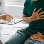 Patient holding chest while doctor takes notes