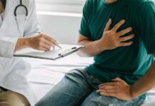 Uncovering New Drivers of Heart Disease Patient holding chest while doctor takes notes