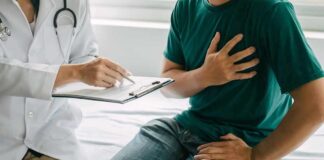 Patient holding chest while doctor takes notes