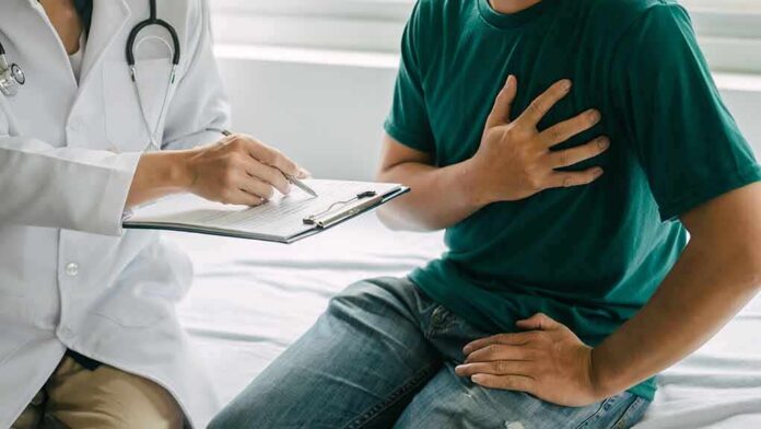 Patient holding chest while doctor takes notes