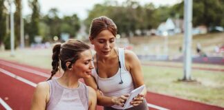 Two women at a running track looking at a tablet
