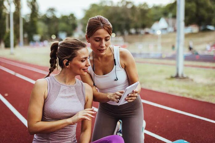 Two women at a running track looking at a tablet