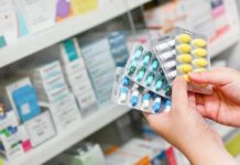 Hands holding blister packs of assorted pills in a pharmacy