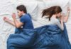 Couple sleeping back to back under a blue blanket