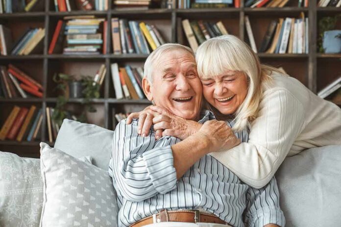 Older couple hugging and laughing on a couch