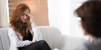 Woman with hand on forehead sitting on couch during counseling session