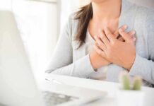 person clutching chest with both hands at a desk