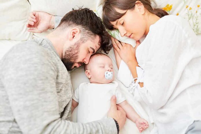 Parents sleeping beside newborn baby