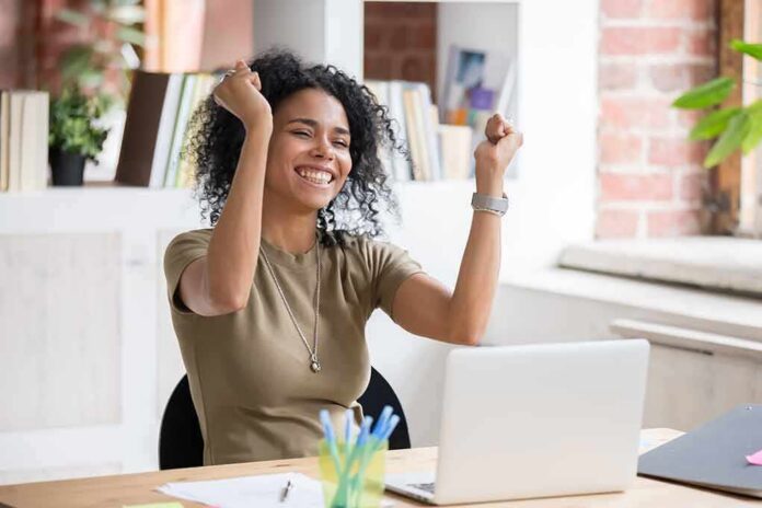Daniella Alonso celebrating at a desk with a laptop