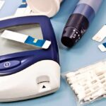Blood glucose monitor with testing strips and a lancing device on a blue background