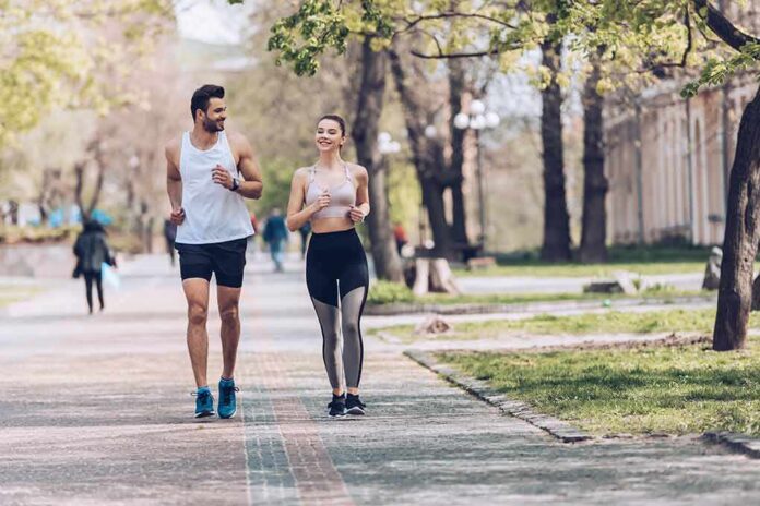 shutterstock_1422371762 Two people jogging together on a tree-lined park path