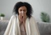 Woman wrapped in a blanket blowing her nose