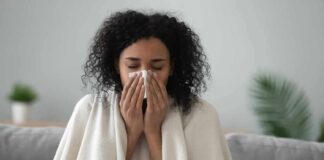 Woman wrapped in a blanket blowing her nose