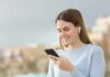 Woman with wireless earbuds using a smartphone outdoors