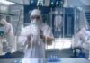 Scientist in hazmat suit using a transparent digital tablet in a lab