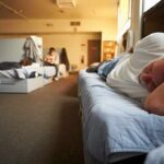 Man resting on a bunk in a shared dormitory room