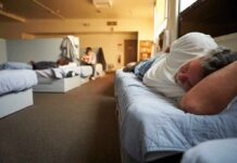 Man resting on a bunk in a shared dormitory room