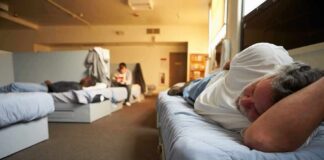Man resting on a bunk in a shared dormitory room