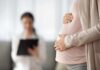 Pregnant woman holding belly during medical visit