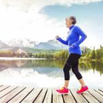Older woman jogging on a wooden dock by a mountain lake