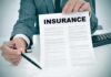 Person in suit holding an insurance document and a pen
