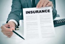Person in suit holding an insurance document and a pen