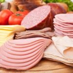 Assorted deli meats and sliced cheese on a wooden board